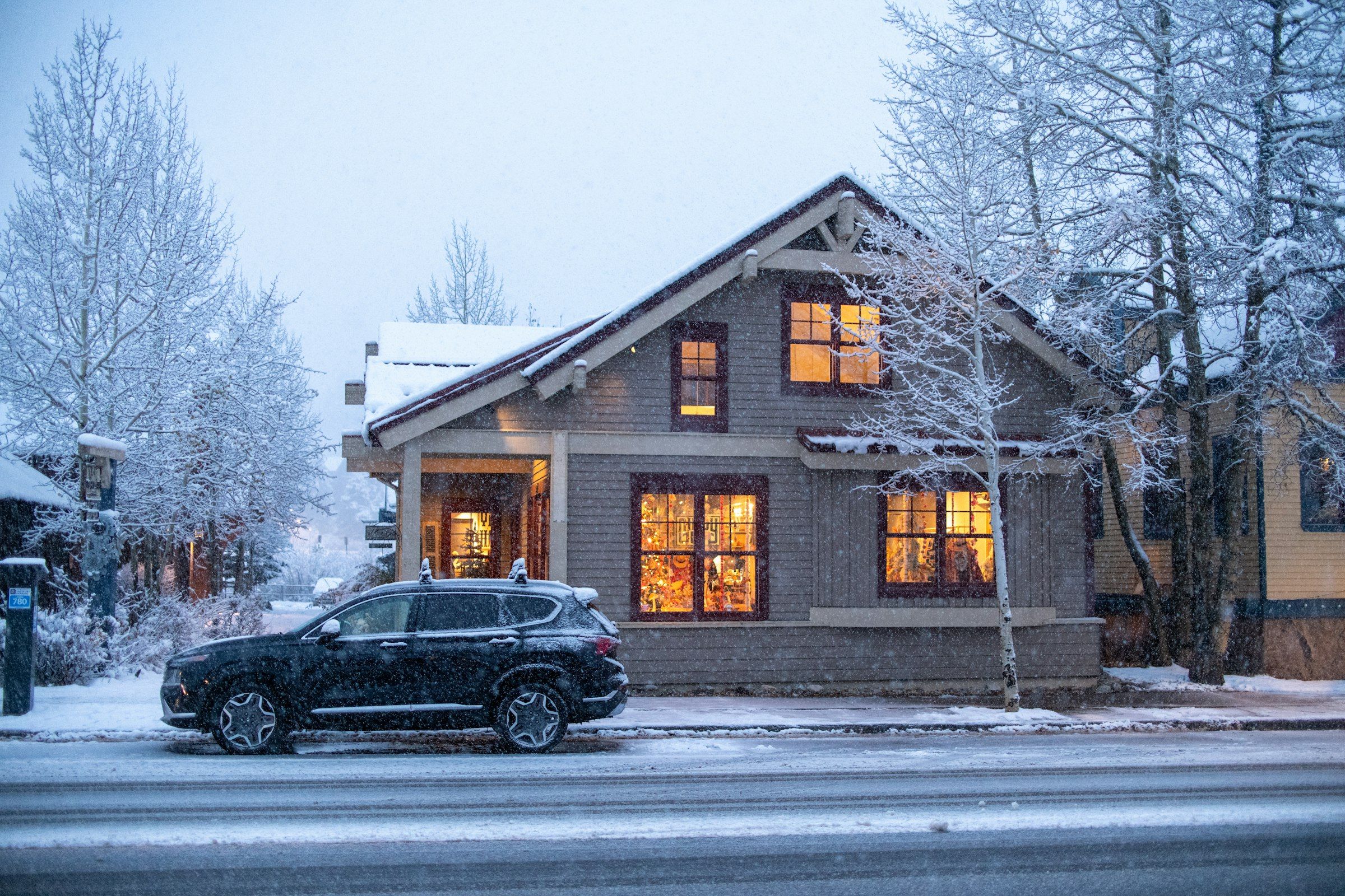 A craftsman house with lit windows on a snowy Colorado street in winter