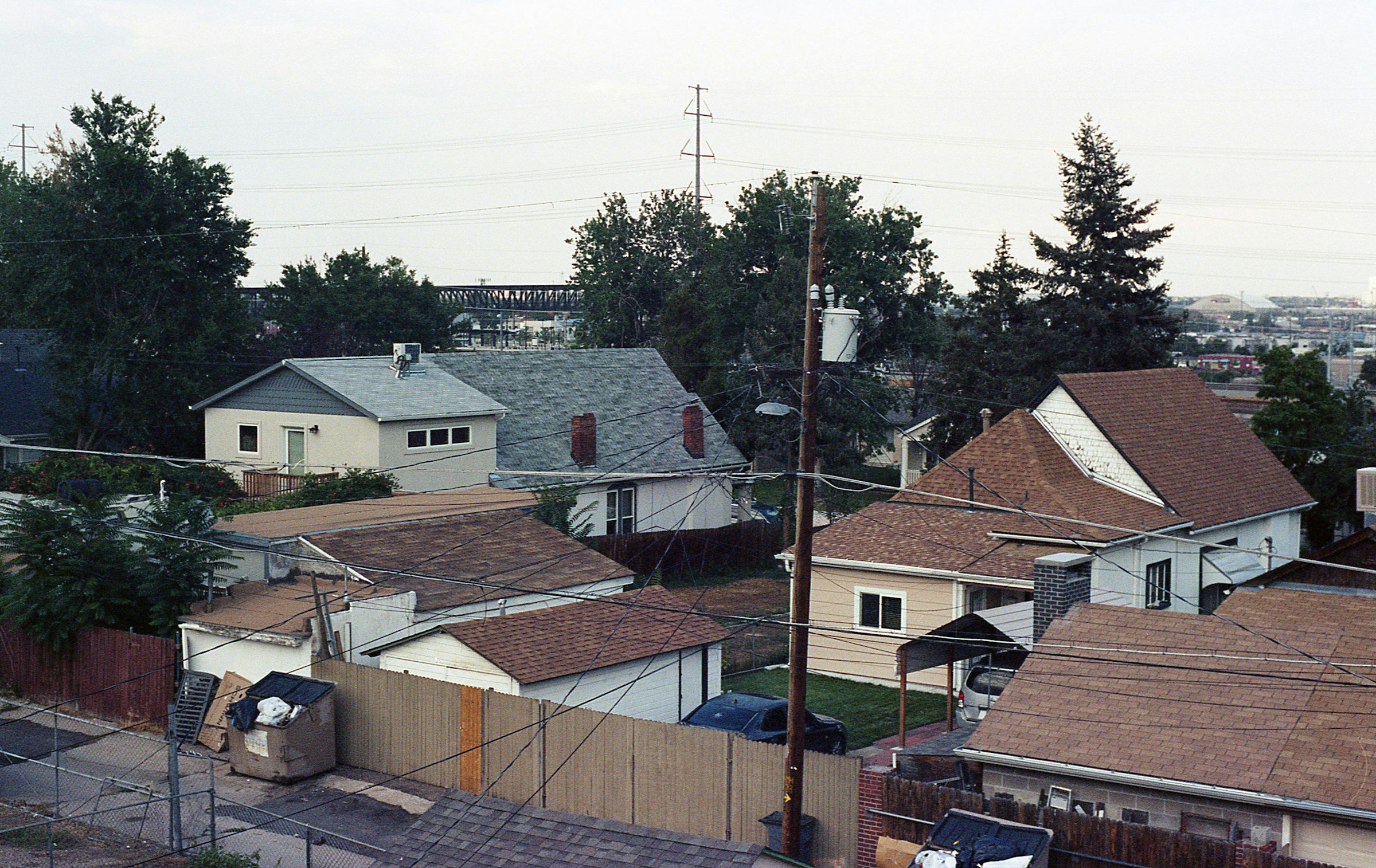 Pitched rooftops of a suburban neighborhood among tall evergreens