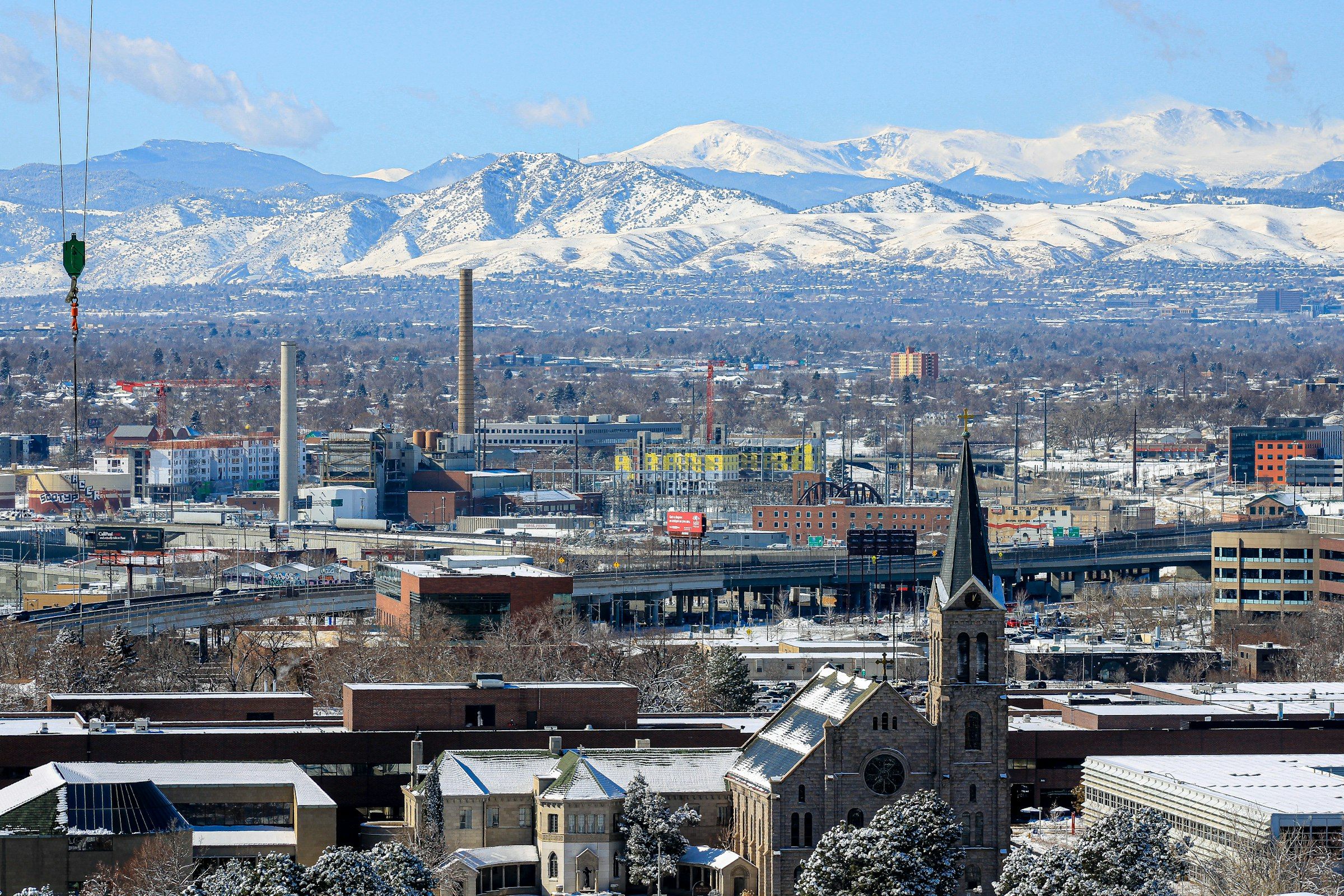 Denver rooftops in winter with snow on the Front Range behind them