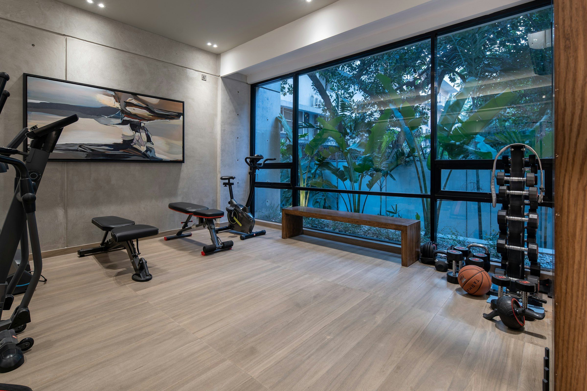 A home gym with a bench, an exercise bike and weights on a light wood floor