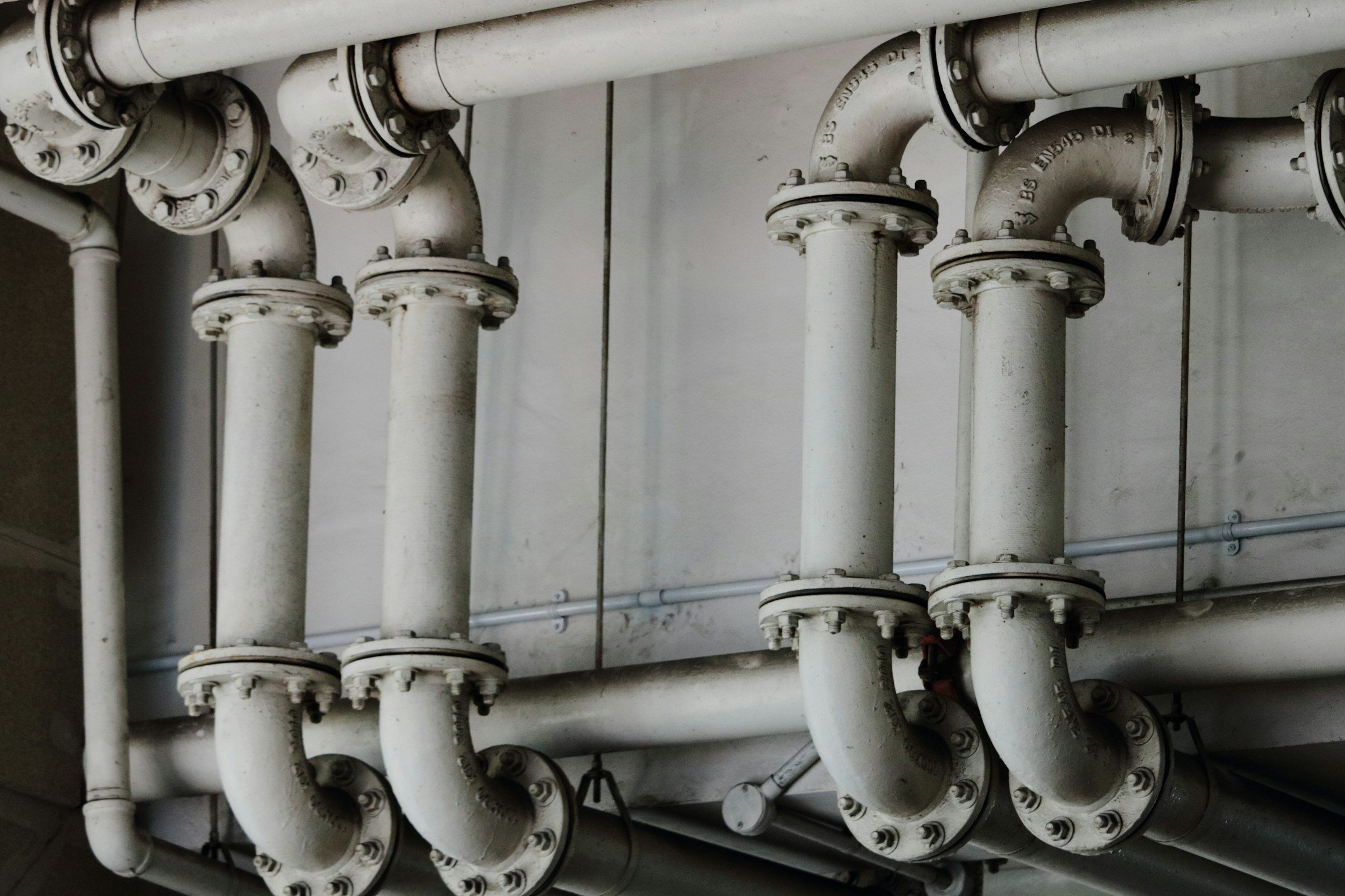 Large drain pipes and fittings running along a wall